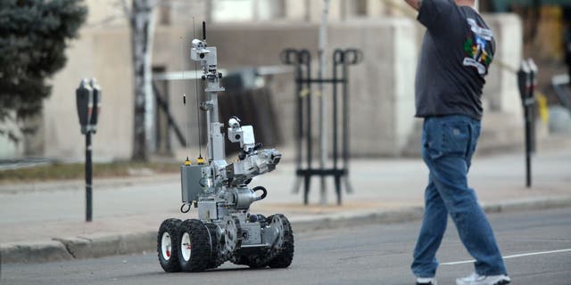 Colorado bomb squad robot gets a hand going under police tape during closures due to a suspicious package.