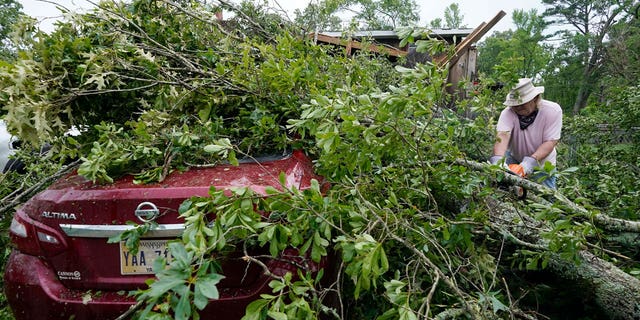 Span McGinty uses his chain saw to cut fallen tree limbs from a tornado-damaged vehicle at his brother's house in Yazoo County, MS, on May 3, 2021. 90% of counties in the United States experienced a weather-related disaster between 2011-2021, according to a report published on Nov. 16, 2022.