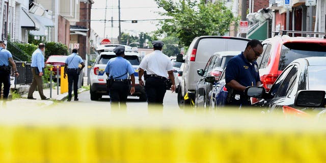 Police officers work at the scene the day after a shooting in Philadelphia